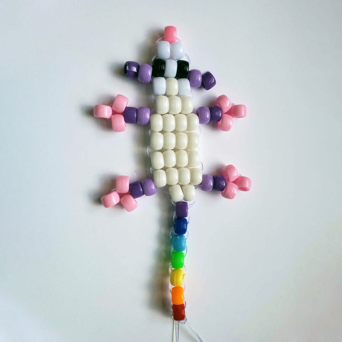 a colorful opossum figure made out of pony beads; it has a rainbow tail!