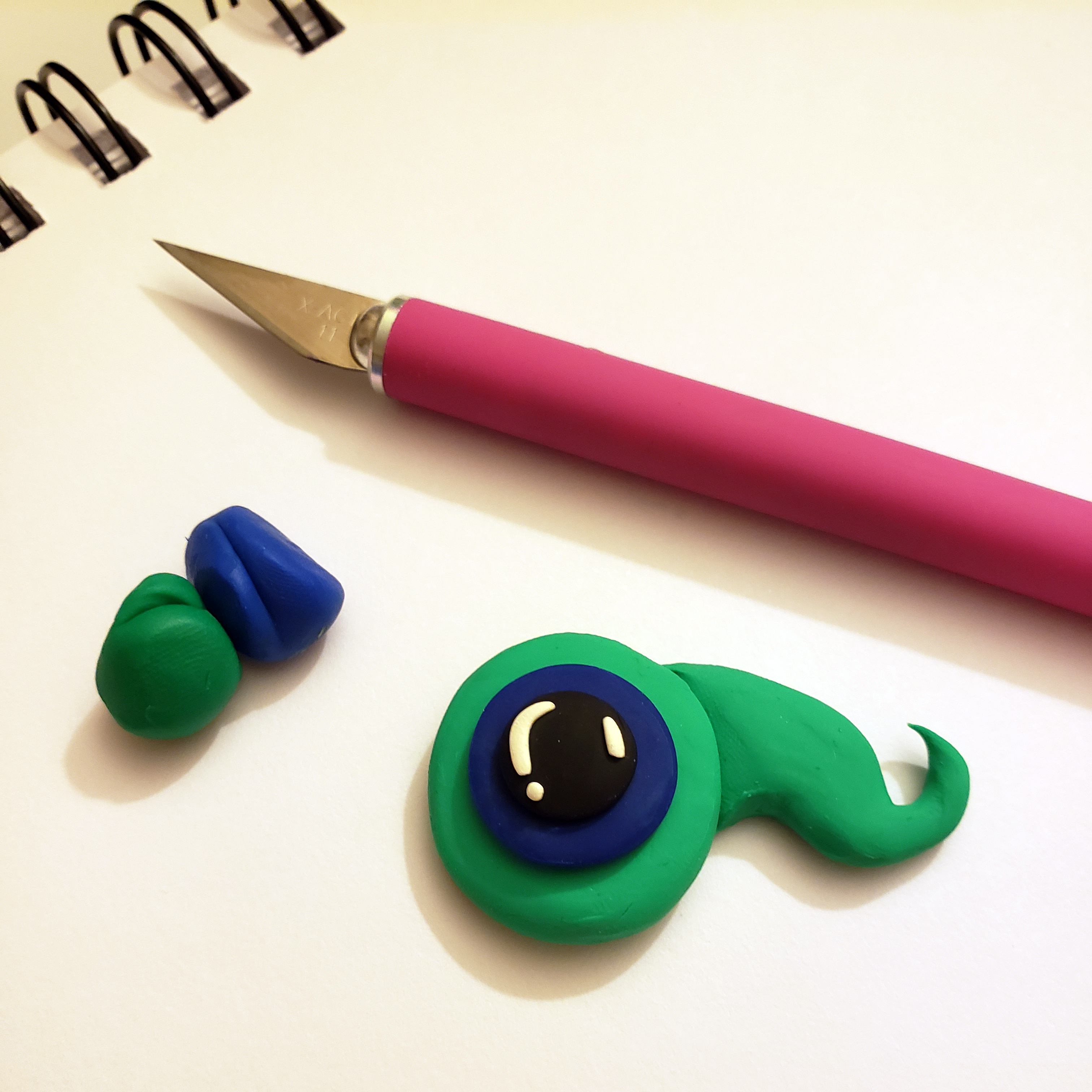 a simple polymer clay sculpt of a green and blue free-floating eyeball, the mascot of Jacksepticeye