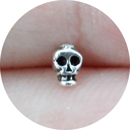 a silver nosestud shaped like a teeny tiny skull